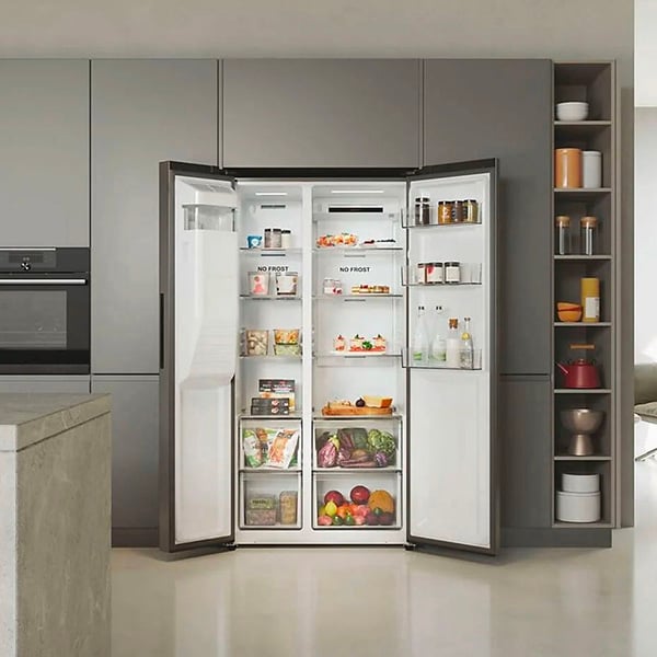 Rfrigrateur side-by-side avec les portes ouvertes, intgr dans une cuisine grise moderne, montrant des aliments frais, des boissons et des produits surgels bien rangs.
