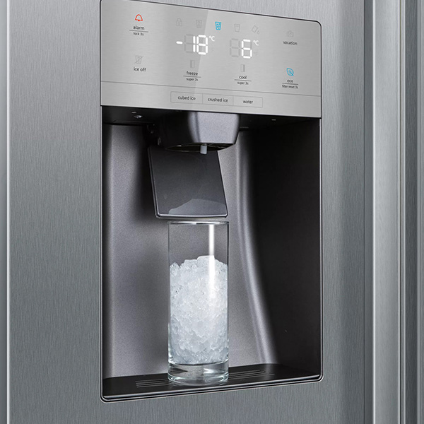 Verre rempli de glace pile sous le distributeur automatique dun rfrigrateur en acier inoxydable.