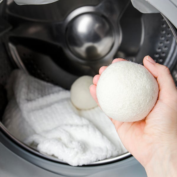 Iemand die droogballen in de droogkast plaatst