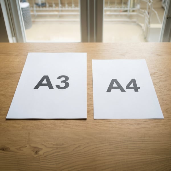 Comparaison entre une feuille A3 et une feuille A4 pos�es c�te � c�te sur une table en bois.