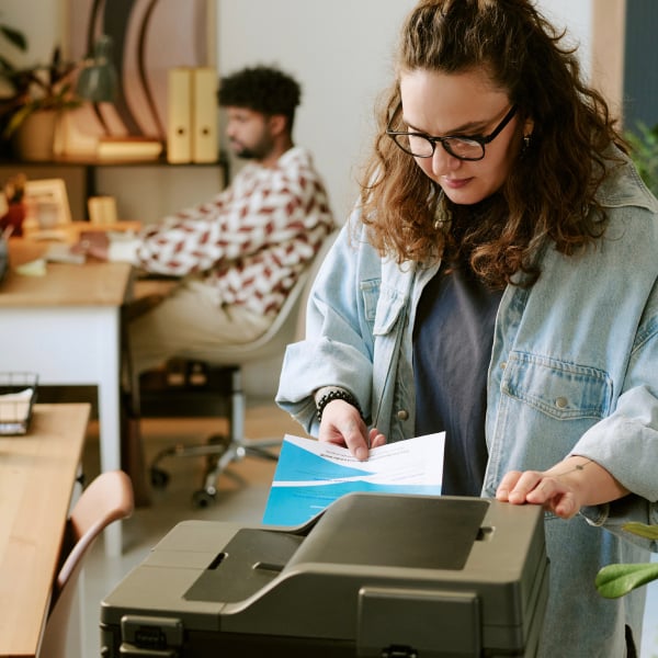 Personne pla�ant des feuilles dans une imprimante multifonction dans un environnement de bureau.