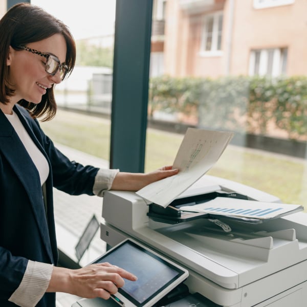 Utilisatrice pla�ant un document dans le chargeur automatique d�une imprimante multifonction avec �cran tactile.