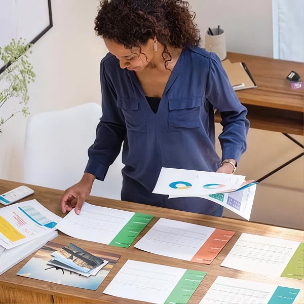 Personne organisant des documents imprim�s sur une table de travail � domicile.