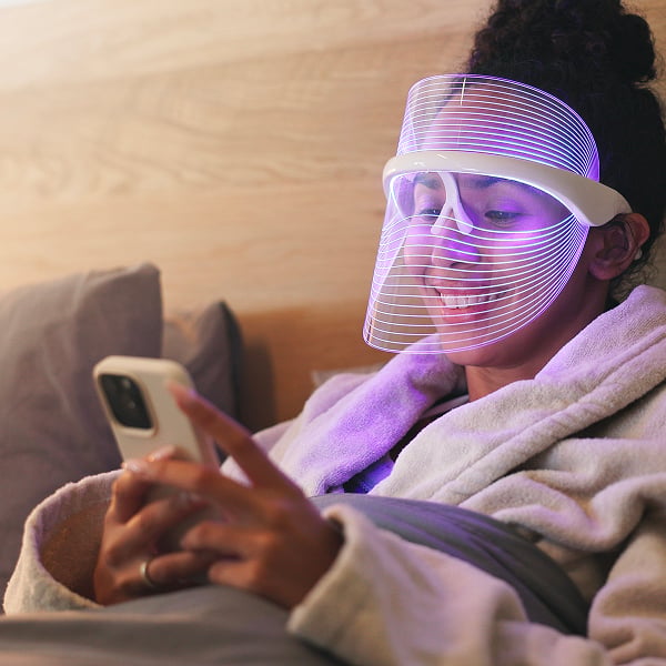 Een vrouw die een led-masker gebruikt in haar zetel