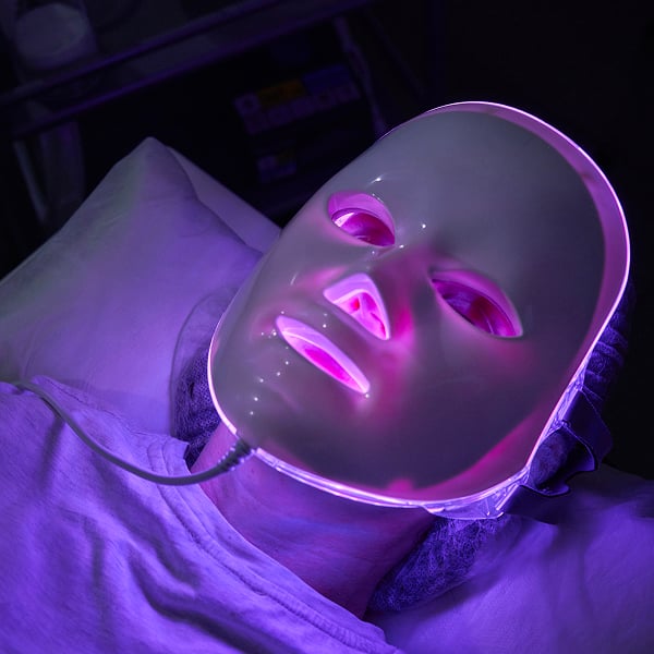 Iemand die een LED-gezichtsmasker met nabij-infrarood licht draagt