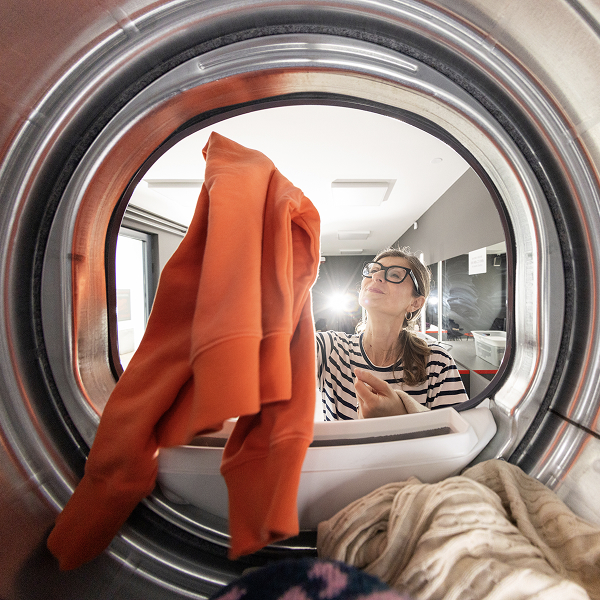 Persoon plaatst kleding in een droogkast.