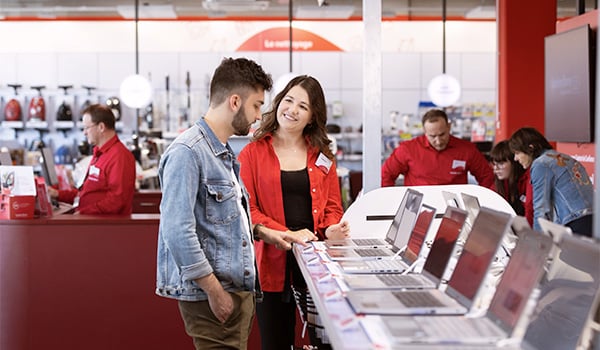 Een verkoopster helpt een klant de juiste laptop te kiezen.