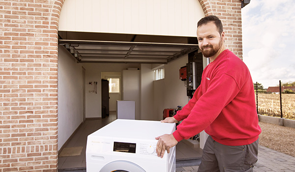 Een bezorger levert een wasmachine aan huis.