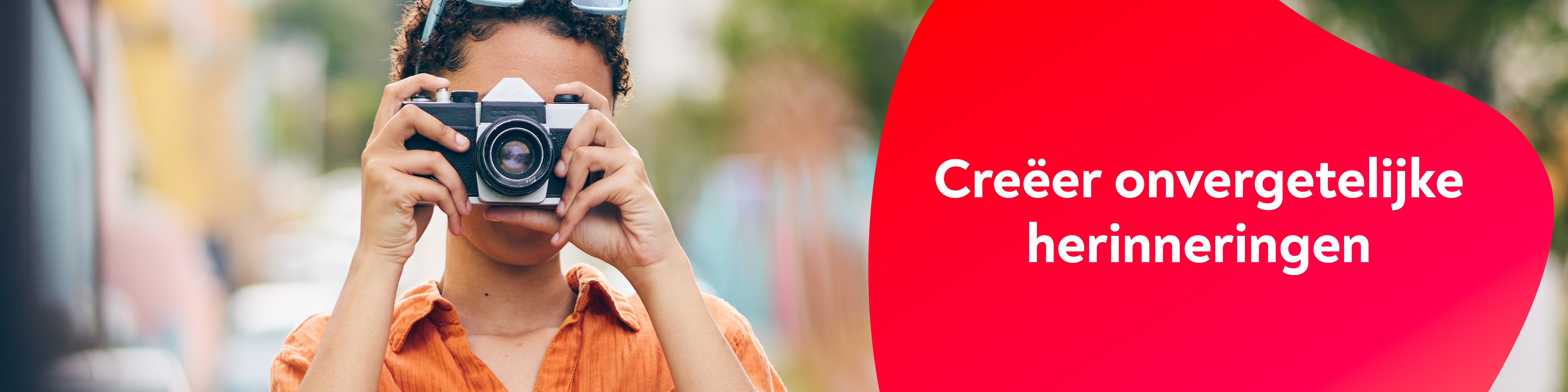 Een vrouw met een spiegelreflexcamera, midden op een landweggetje.