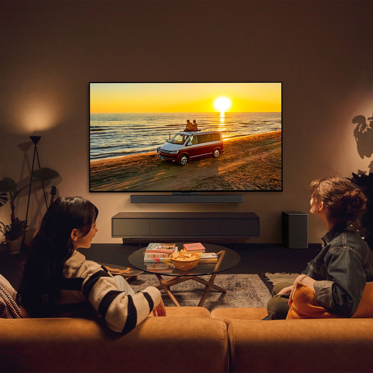 Een man en een vrouw kijken naar een vakantiefoto op televisie vanaf hun bank