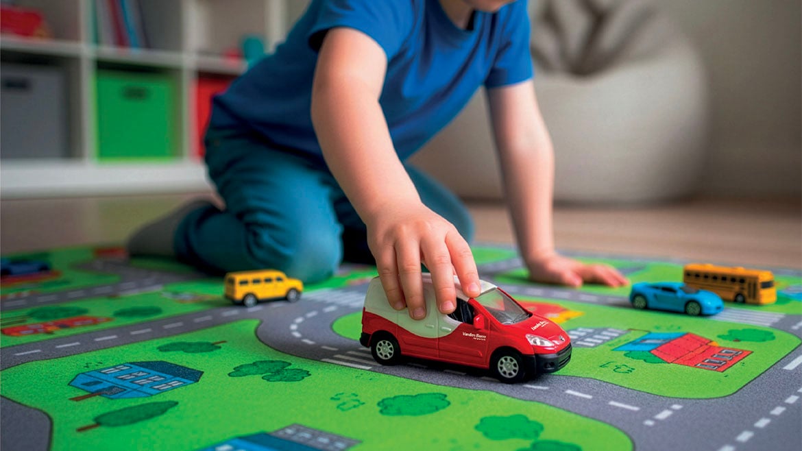 Een kind speelt met een speelgoedversie van de rood-witte Vanden Borre-bestelwagen.