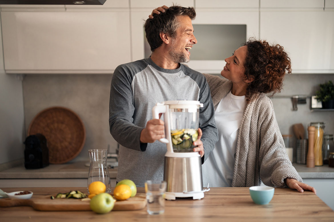 Een koppel, vrouw en man, zijn samen aan het koken met een blender.