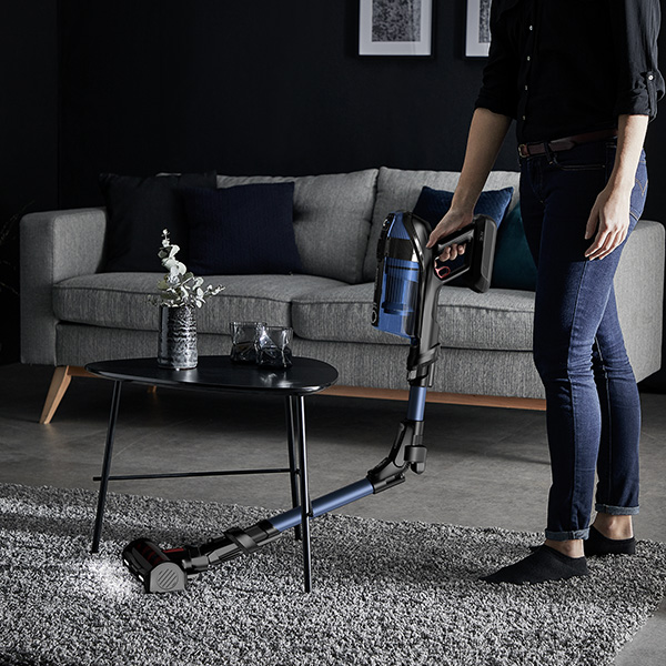 Een vrouw die onder een tafel stofzuigt met 