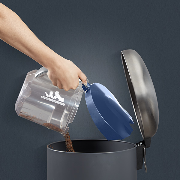 Een persoon die de bak van de Rowenta Compact Power XXL stofzuiger in een prullenbak leegt