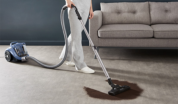 Een vrouw die aarde opzuigt in haar woonkamer met een Rowenta Compact Power XXL stofzuiger