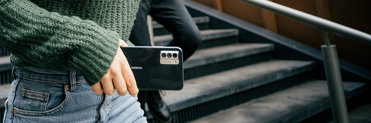 Een vrouw die buiten haar Nokia G22-smartphone in haar hand houdt