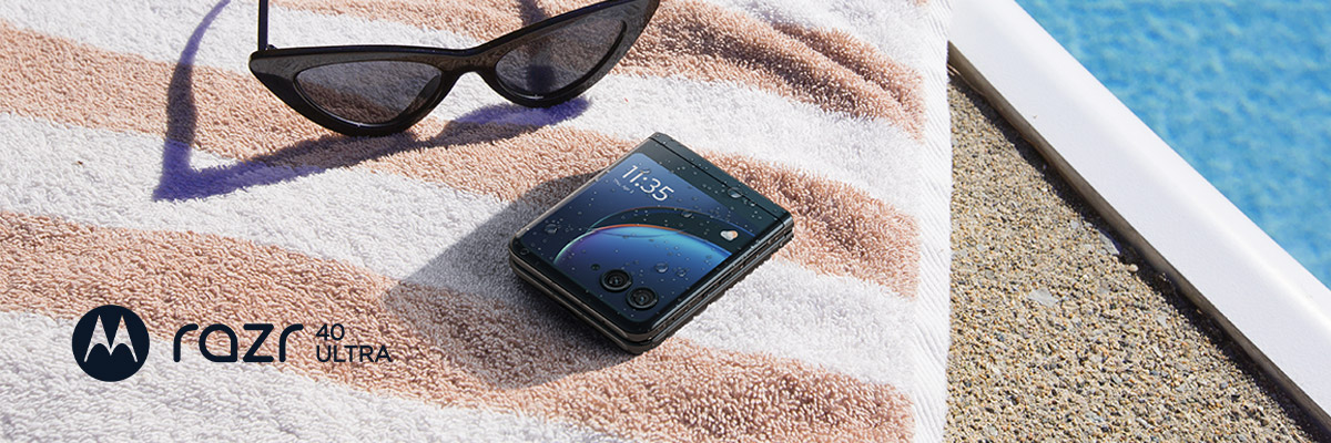 Een opvouwbare Motorola razr 40 ultra-smartphone op een strandhanddoek met zonnebril