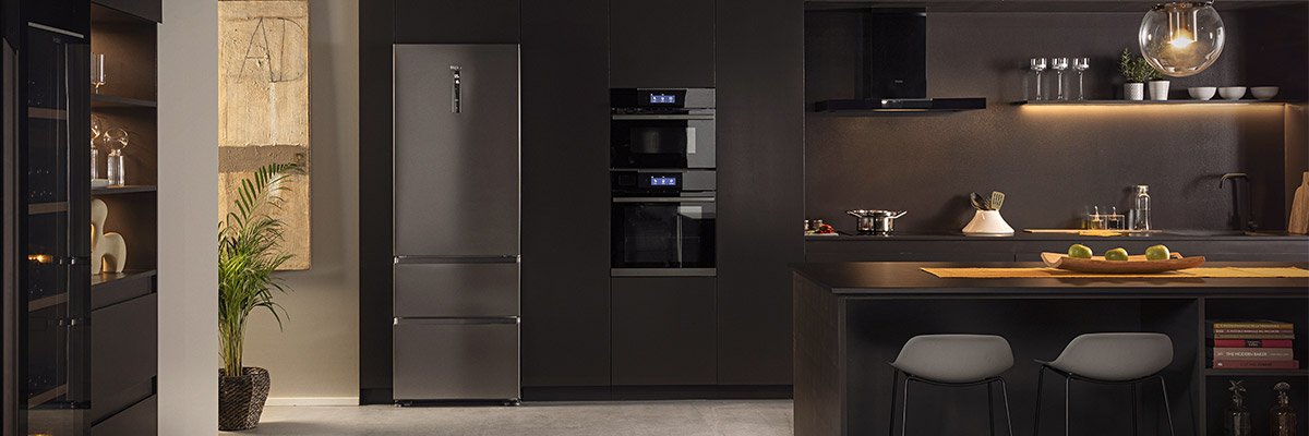 Keuken in zwarte tinten uitgerust met een Haier-koelkast 