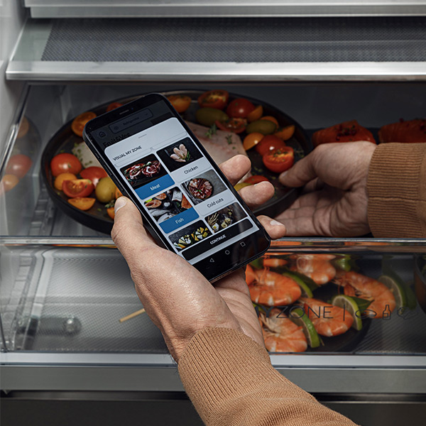 Een persoon die de hOn-app gebruikt met zijn geopende Haier-koelkast 