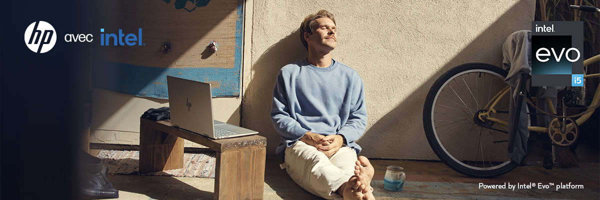 Un homme assis par terre au soleil avec son PC portable HP  