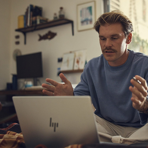 Un homme assis dans son salon qui travaille avec son PC portable HP 