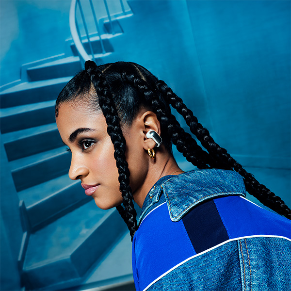 Une dame vtue de bleu qui porte les couteurs ouverts sans fil noirs devant un escalier.