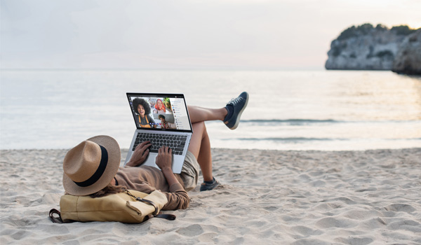 Meneer op het strand met zijn laptop online aan het chatten