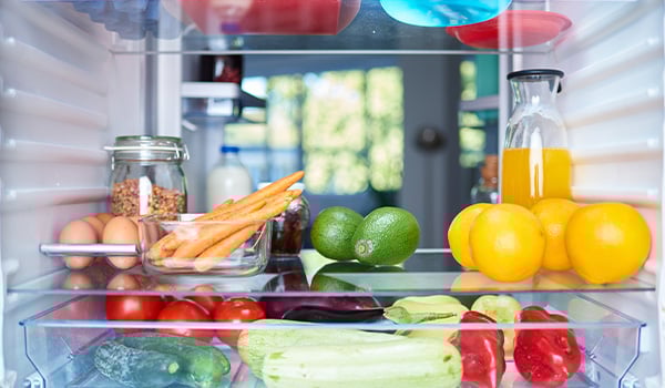 Vue de l'intrieur du frigo : lgumes, jus d'orange, ufs sur une clayette. Et lgumes verts, poivrons et tomates dans le bac  lgumes.