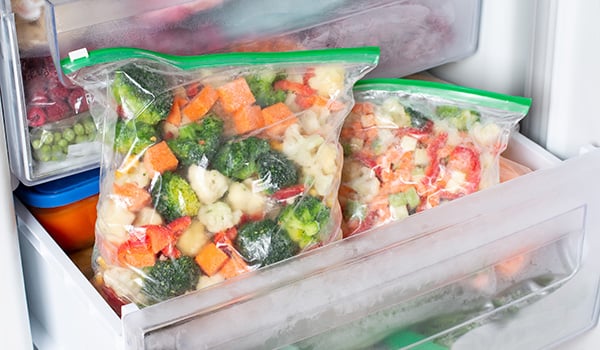 Tiroir d'un conglateur ouvert, o on voit des lgumes emballs dans des sachets zip.