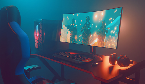 Poste informatique de gaming avec un �cran incurv� affichant une sc�ne de jeu vid�o d�action, un clavier, une souris, un casque et une tour �clair�e