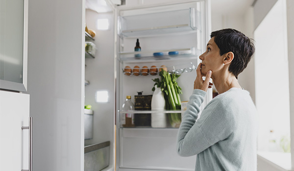 Personne debout dans une cuisine observant le contenu d�un r�frig�rateur ouvert contenant des aliments et des boissons