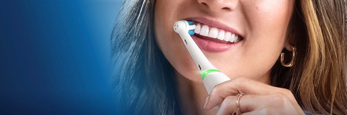 Persoon die een elektrische tandenborstel op de tanden gebruikt, close‑up van het onderste deel van het gezicht