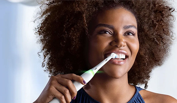 Close‑up van een persoon die een elektrische tandenborstel gebruikt met de borstelkop op de tanden