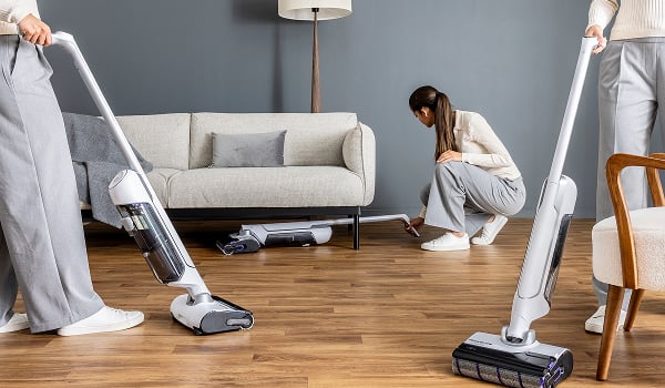 Een vrouw reinigt onder de zetel met de flexibele steel van de X-Clean 10