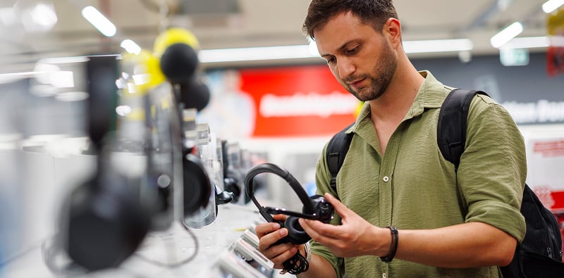Persoon vergelijkt hoofdtelefoons in een elektronicawinkel.