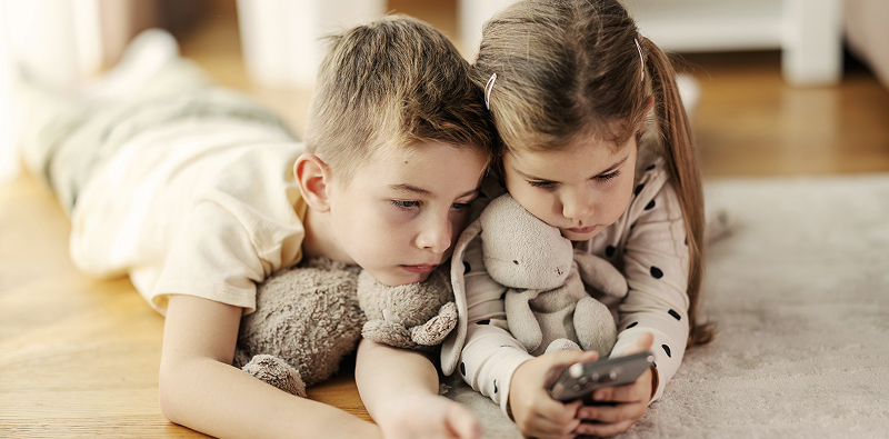 Deux enfants regardent un smartphone.