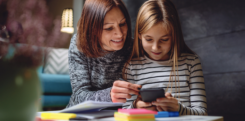 Adulte et enfant regardent un smartphone.