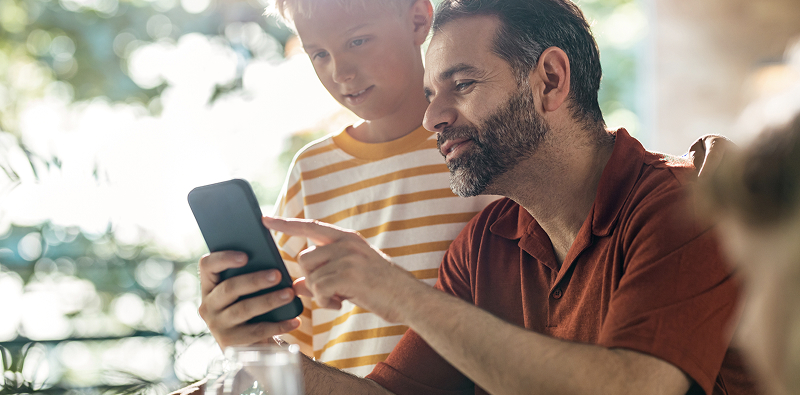 Adulte et enfant regardent un smartphone.