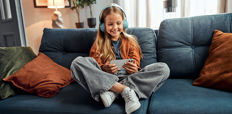 Personne avec un casque audio utilisant un smartphone sur un canap�.